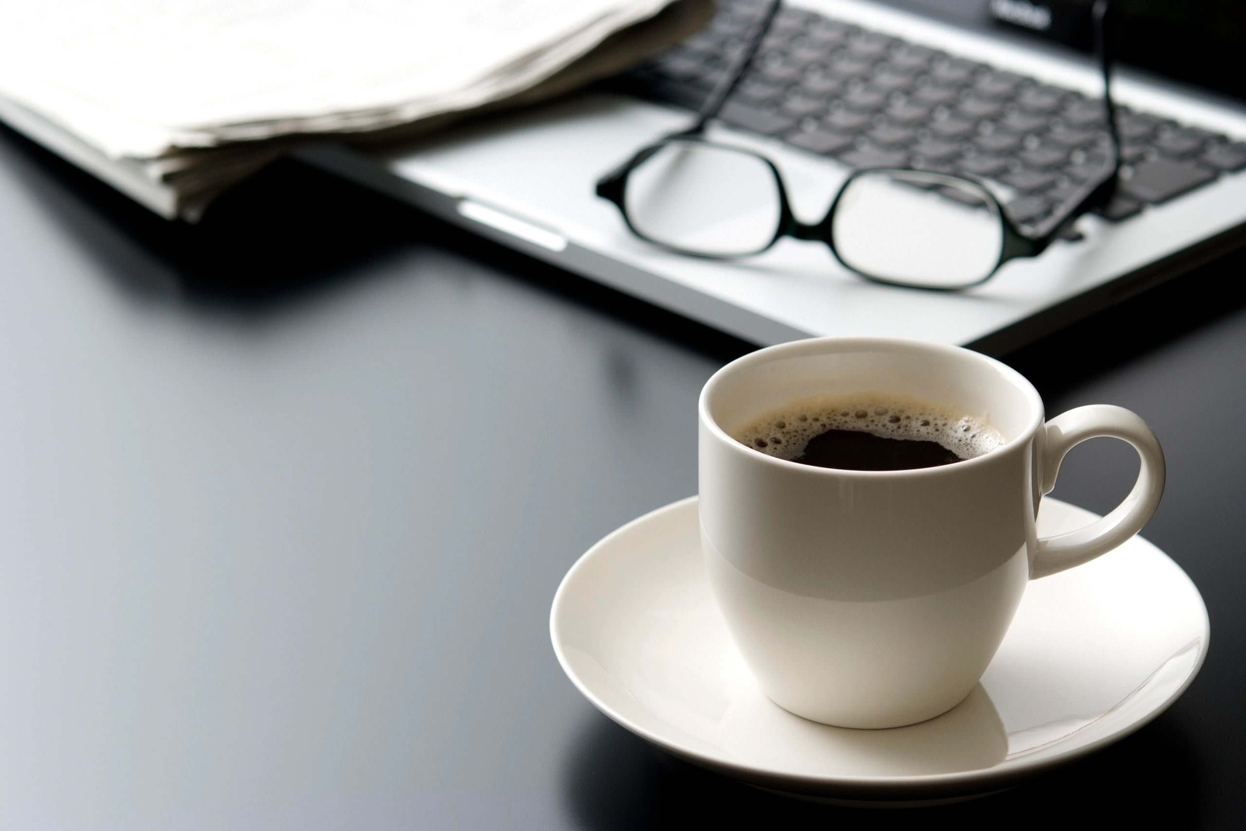 Coffee cup beside a laptop on an office desk